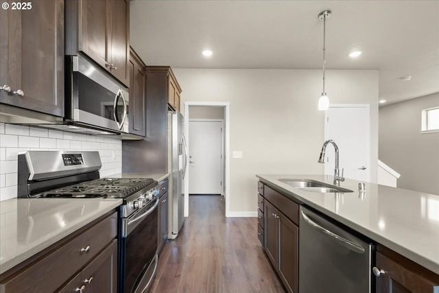 kitchen featuring appliances with stainless steel finishes, light countertops, a sink, and tasteful backsplash