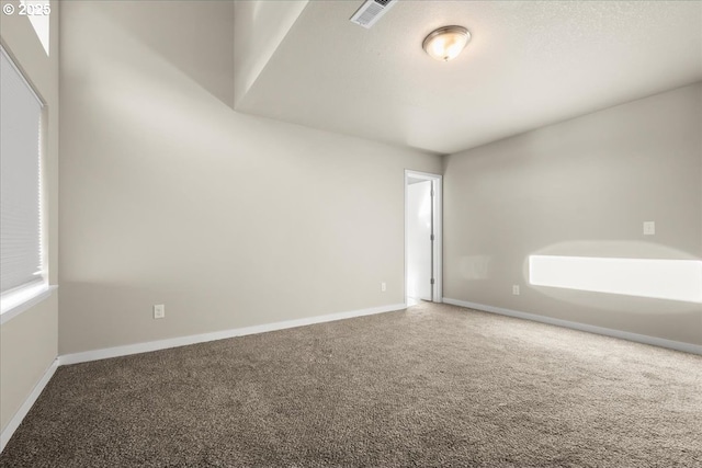 empty room with a wealth of natural light, carpet, visible vents, and baseboards