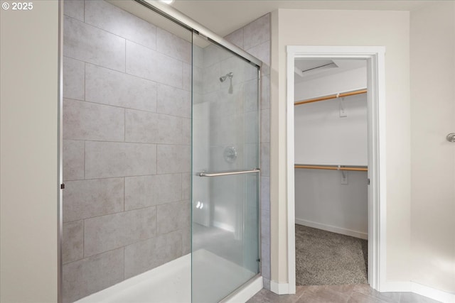 bathroom featuring a spacious closet, a shower stall, and baseboards