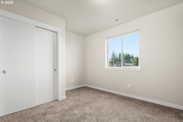 unfurnished bedroom featuring a closet, visible vents, light carpet, and baseboards