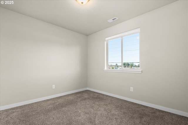 spare room with carpet floors, visible vents, and baseboards