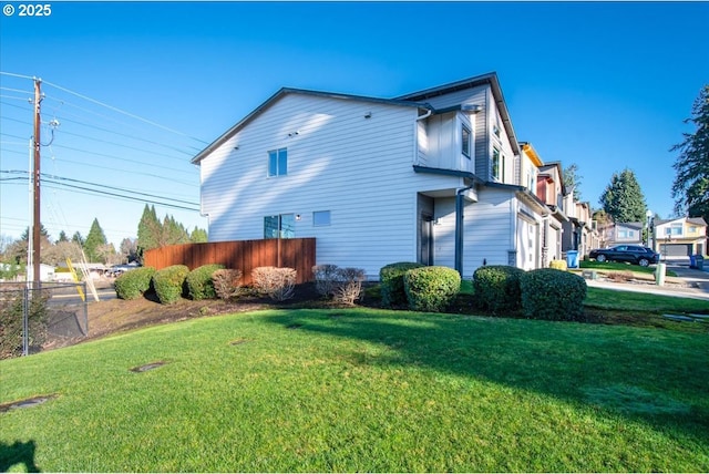 view of home's exterior with fence and a yard