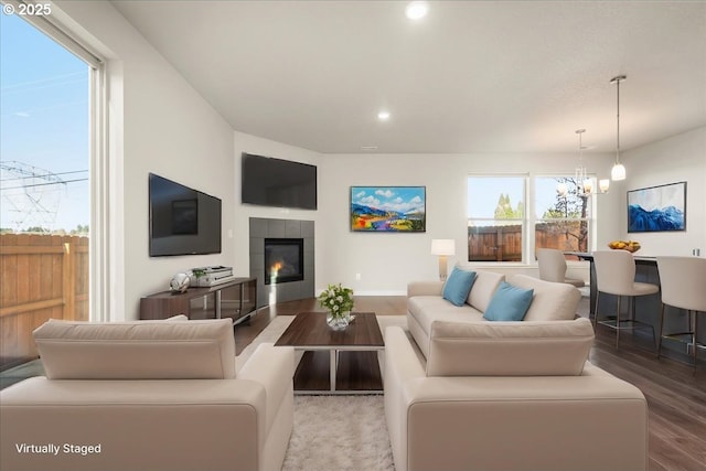 living room featuring a tiled fireplace, a chandelier, wood finished floors, and recessed lighting