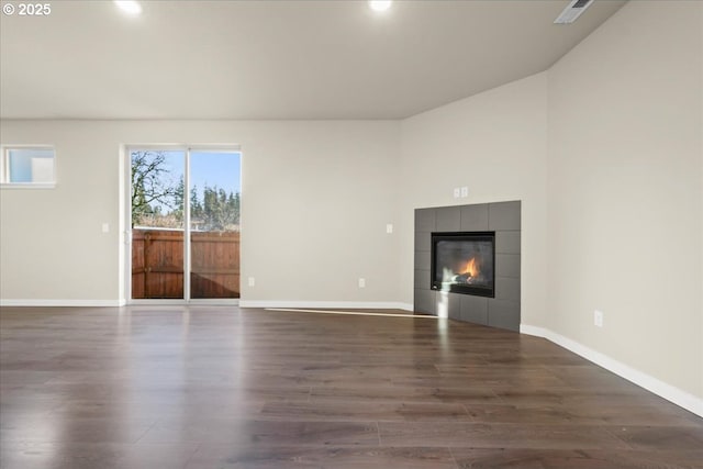 unfurnished living room with wood finished floors, a tile fireplace, and baseboards