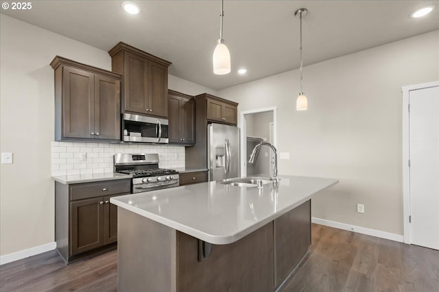 kitchen featuring appliances with stainless steel finishes, a sink, dark wood finished floors, and tasteful backsplash