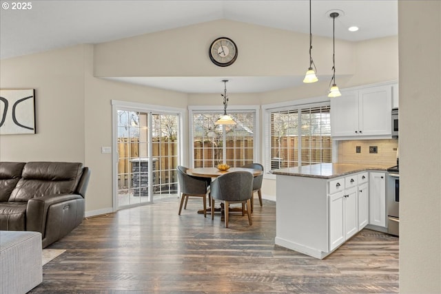 kitchen featuring hanging light fixtures, stone counters, dark wood-type flooring, white cabinets, and backsplash