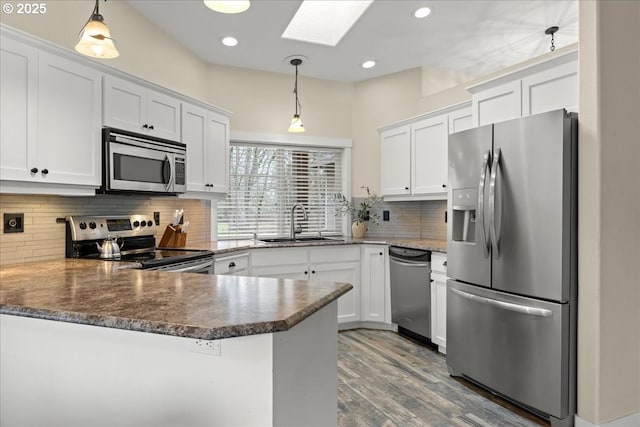 kitchen featuring kitchen peninsula, stainless steel appliances, decorative light fixtures, and white cabinetry