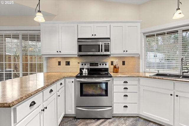 kitchen featuring sink, stainless steel appliances, white cabinets, and hanging light fixtures