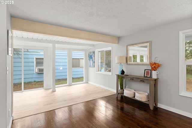 doorway to outside featuring wood-type flooring, beam ceiling, cooling unit, and a textured ceiling