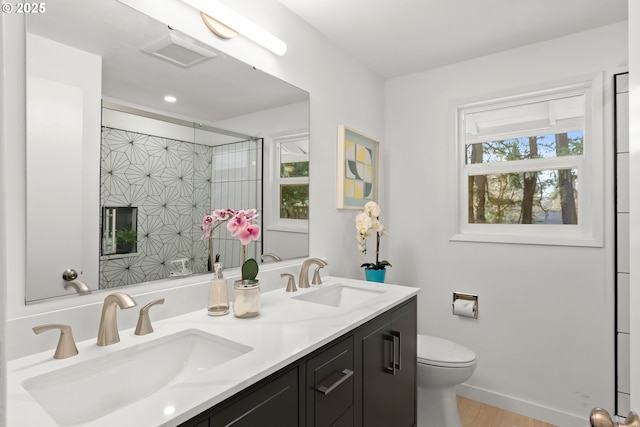 bathroom with vanity, toilet, tiled shower, and wood-type flooring