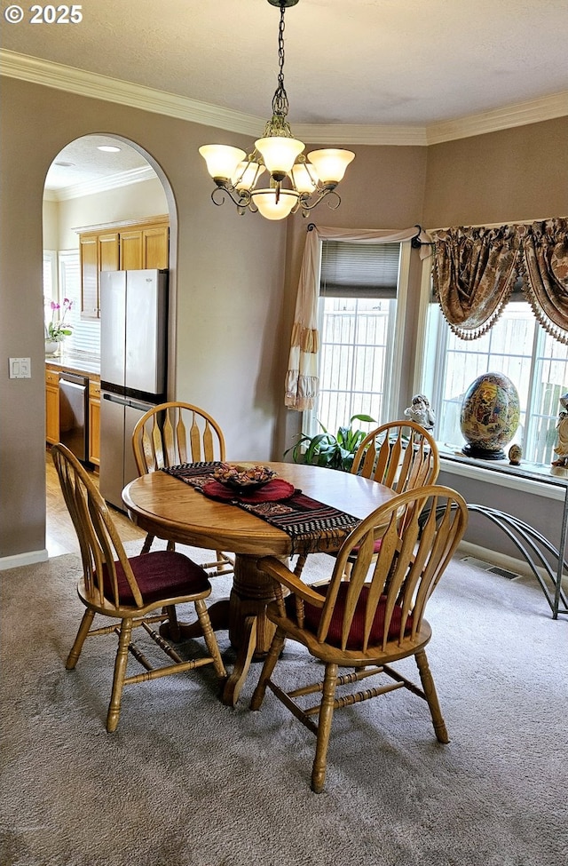 1270 Hidden Creek Dr, Keizer, OR 97303 - dining room with light colored carpet, arched walkways, a chandelier, plenty of natural light, and crown molding