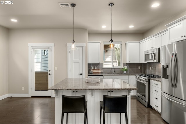14152 SW Compass Dr, Beaverton, OR 97005 - kitchen with appliances with stainless steel finishes, tasteful backsplash, recessed lighting, a center island, and light stone countertops