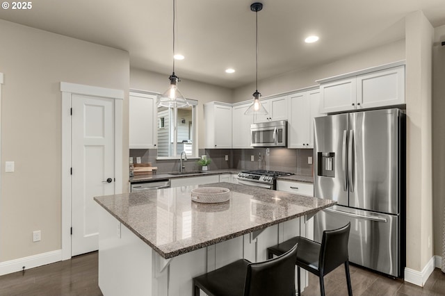 14152 SW Compass Dr, Beaverton, OR 97005 - kitchen featuring stainless steel appliances, white cabinetry, tasteful backsplash, a kitchen island, and a breakfast bar