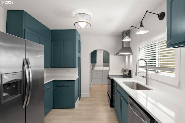 11744 SW 61st Ave, Portland, OR 97219 - kitchen featuring appliances with stainless steel finishes, washing machine and clothes dryer, light wood-style flooring, light countertops, and wall chimney exhaust hood