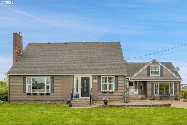 back of property with a lawn, a chimney, and roof with shingles