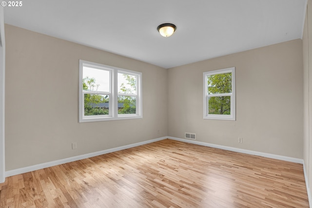 empty room with baseboards, visible vents, and light wood-style flooring