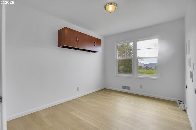 unfurnished room featuring visible vents, light wood finished floors, and baseboards