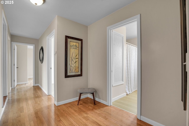 corridor with baseboards and light wood finished floors