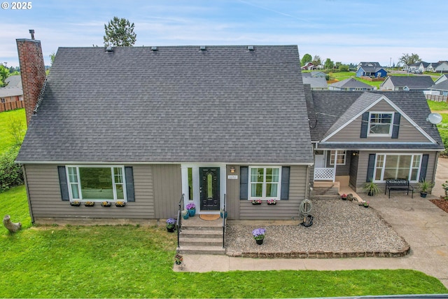 view of front of house featuring a patio, a front lawn, roof with shingles, and a chimney