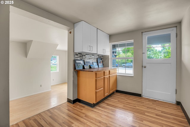 kitchen with light wood-style floors, baseboards, and a healthy amount of sunlight