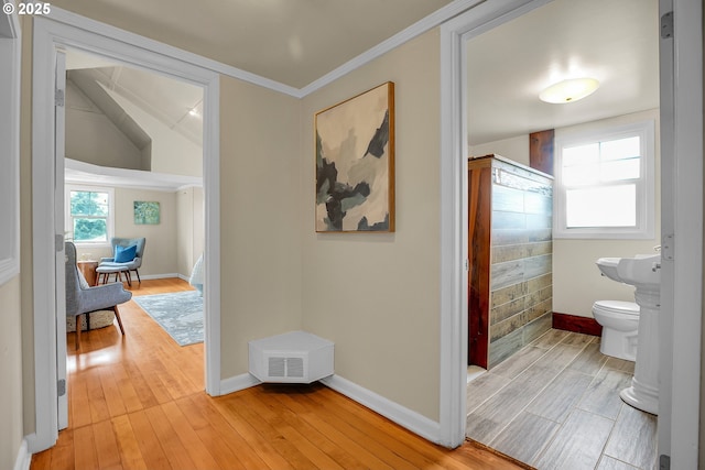 corridor featuring crown molding, baseboards, visible vents, and light wood finished floors