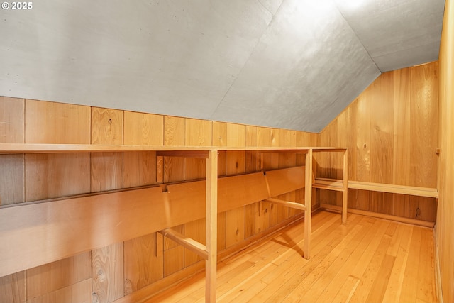 additional living space featuring wooden walls, hardwood / wood-style flooring, lofted ceiling, and a sauna