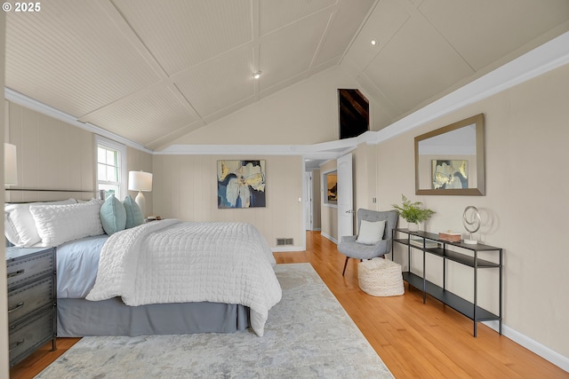 bedroom with baseboards, visible vents, wood finished floors, and lofted ceiling