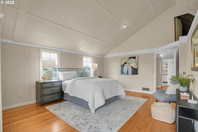 bedroom with baseboards, visible vents, light wood finished floors, and lofted ceiling