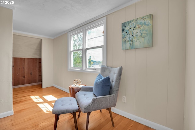 sitting room featuring crown molding, baseboards, and wood finished floors