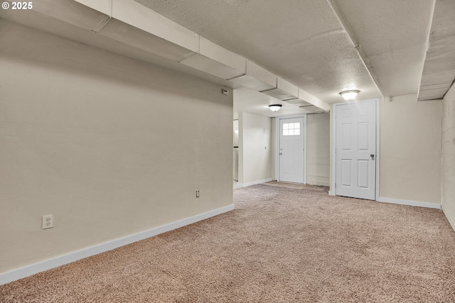 basement featuring baseboards, carpet flooring, and a textured ceiling