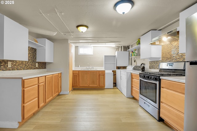 kitchen featuring gas range, tasteful backsplash, open shelves, a sink, and light wood finished floors