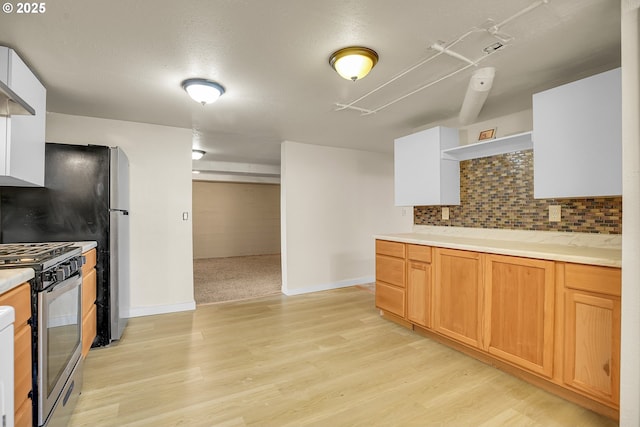 kitchen with backsplash, gas range, open shelves, light wood-type flooring, and light countertops