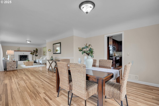 dining space with light wood-style floors, baseboards, and visible vents