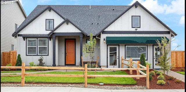 view of front of home featuring board and batten siding, roof with shingles, and a fenced front yard