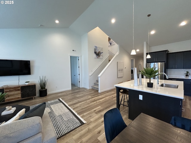 living area with baseboards, light wood-type flooring, stairs, and high vaulted ceiling