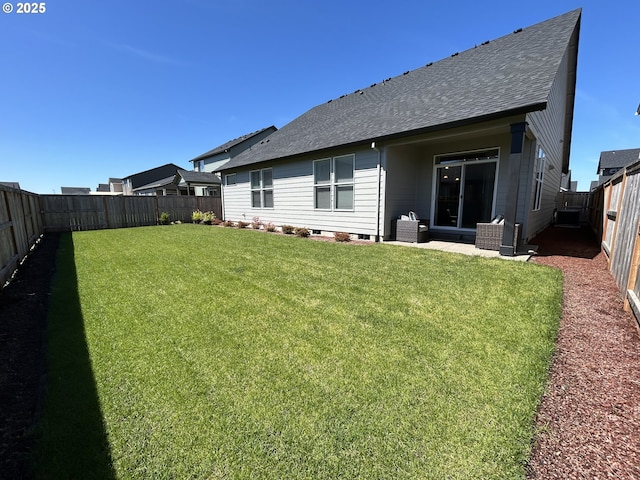 rear view of house with a shingled roof, a fenced backyard, and a yard