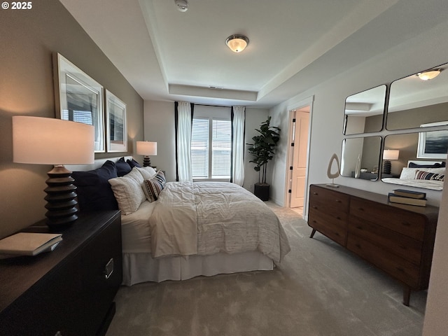 bedroom with light carpet and a tray ceiling