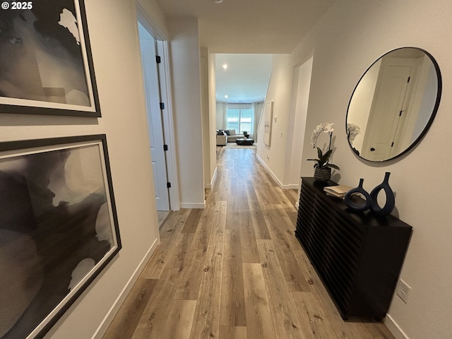 hallway featuring recessed lighting, baseboards, and light wood-type flooring