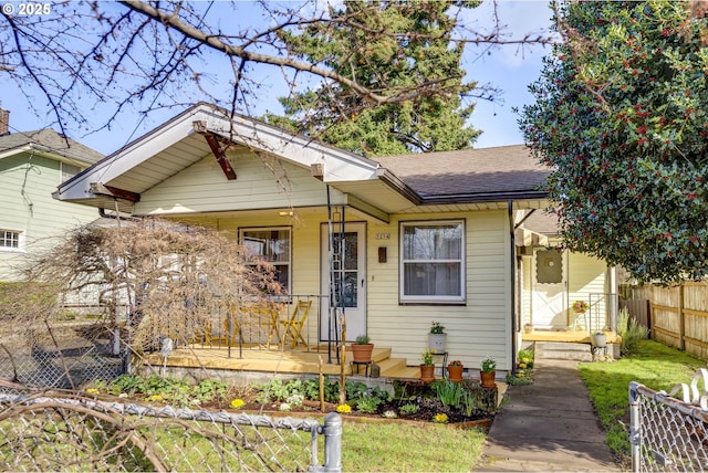 bungalow-style home featuring covered porch, roof with shingles, and fence