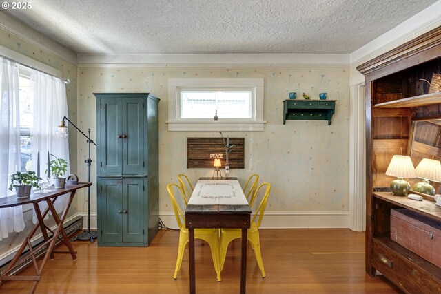 dining room featuring baseboards, light wood-style floors, and a textured ceiling