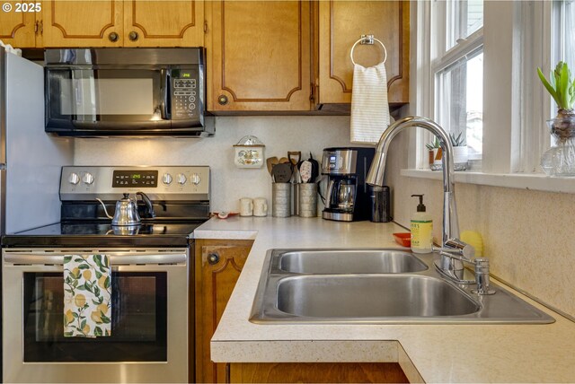 kitchen featuring a sink, light countertops, black microwave, and stainless steel range with electric cooktop