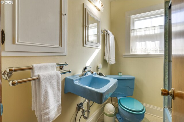 half bath featuring toilet, baseboards, and a sink