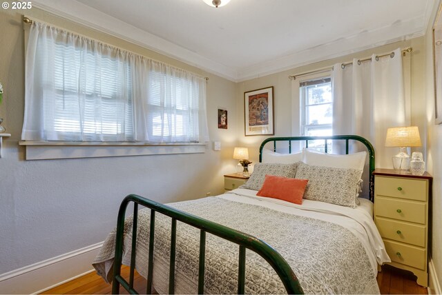 bedroom with wood finished floors, baseboards, and ornamental molding