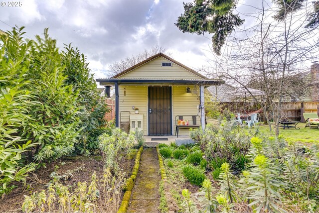 shotgun-style home featuring fence and covered porch