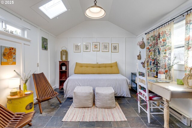 bedroom featuring vaulted ceiling with skylight, a decorative wall, and stone tile flooring