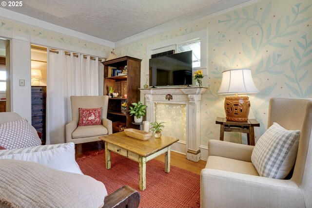 living area with a textured ceiling, wood finished floors, a fireplace, and wallpapered walls