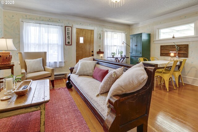 living area with wallpapered walls, a baseboard heating unit, hardwood / wood-style floors, and a textured ceiling