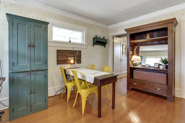 dining area with light wood-style floors, baseboards, and a textured ceiling