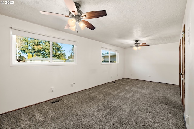 spare room featuring carpet, visible vents, ceiling fan, and a textured ceiling