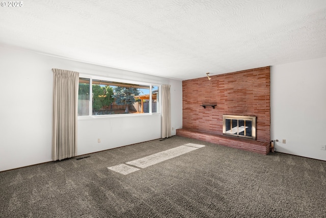 unfurnished living room featuring carpet, a textured ceiling, a brick fireplace, and visible vents